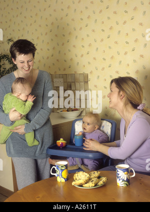 Le donne con i loro bambini in chat e ridere insieme in una cucina Foto Stock