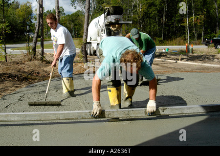 Mason lavoratori cemento pour strada in una nuova casa progetto di costruzione Foto Stock