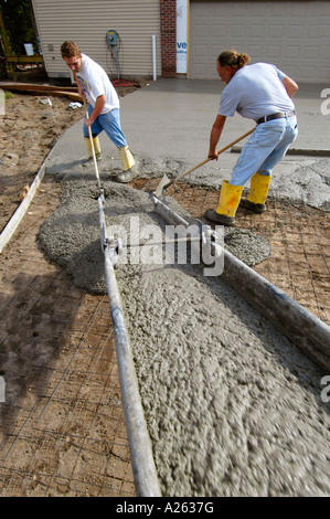 Mason lavoratori cemento pour strada in una nuova casa progetto di costruzione Foto Stock