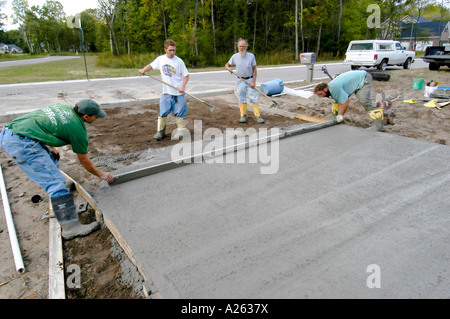 Mason lavoratori cemento pour strada in una nuova casa progetto di costruzione Foto Stock