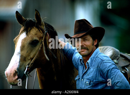 Un felice operosi cowhand ritorna alla casa del suo ranch del Texas dopo una lunga giornata di branding di una mandria di bovini longhorn. Foto Stock