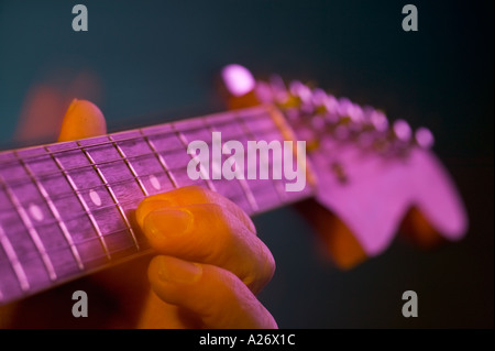 Mans dita spiumatura stringhe su un parafango per la chitarra elettrica Foto Stock