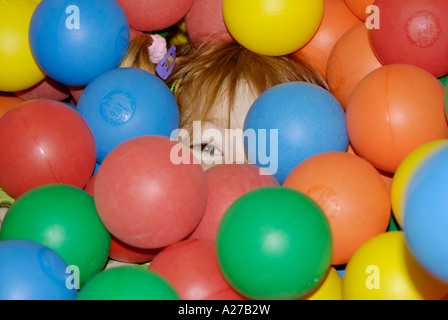 Bambino nuota e gioca con molte sfere Foto Stock