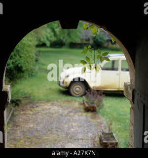 Una vecchia Citroen 2CV in un giardino alla francese visto attraverso un arco in pietra Foto Stock