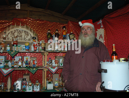 L'uomo la vendita di vino brulé e ornamenti Natale Natale in stallo del mercato Foto Stock