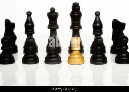 Bianco singolo pezzo degli scacchi in piedi da solo in un gruppo di colore nero di pezzi di scacchi che simboleggia un certo numero di concetti Foto Stock