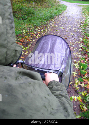 Madre spingendo il bambino nel passeggino sul giorno di pioggia Foto Stock