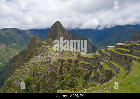 Una classica vista del magnifico antico sito Inca di Machu Picchu in Perù con 2 turisti (in alto a destra) per visualizzare la scala. Foto Stock