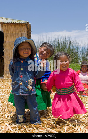 Bambini locali su una delle isole di canne del lago Titicaca giocando e ridendo pongono per la fotocamera. Foto Stock