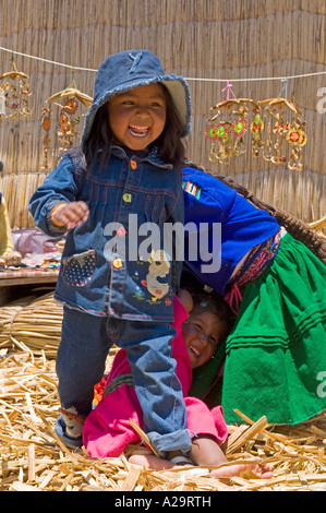 Bambini locali su una delle isole di canne del lago Titicaca giocando e ridendo pongono per la fotocamera. Foto Stock