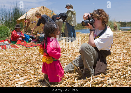 I turisti scattare foto di bambini vestiti in abiti tradizionali su una delle isole di canne sul lago Titicaca. Foto Stock