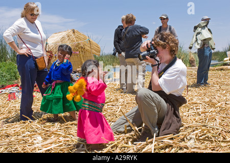 I turisti scattare foto di bambini vestiti in abiti tradizionali su una delle isole di canne sul lago Titicaca. Foto Stock