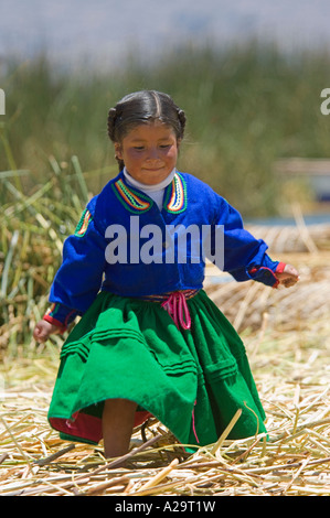 Una giovane ragazza in abiti tradizionali su una delle isole di canne del lago Titicaca pongono per la fotocamera. Foto Stock