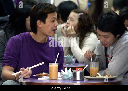 Gli amici di mangiare in un ristorante locale mentre la donna dietro di essi cambia espressione, RAS di Hong Kong Foto Stock