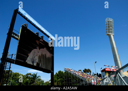 Grande schermo per esterni che mostra il cricket azione, con luce pilone in background Foto Stock