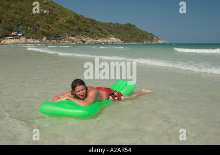 Thailandia Ko Phangan Pha Ngan Hat rin Haad Rin sunrise beach uomo galleggiante sul letto gonfiabile in fondali bassi Foto Stock