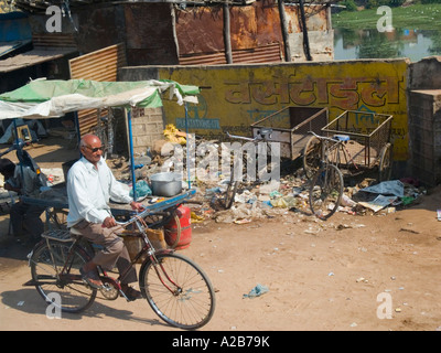 Tipica città sporca scena di strada con la pila di spazzatura uomo locale in bicicletta da stallo del mercato del Madhya Pradesh India Foto Stock