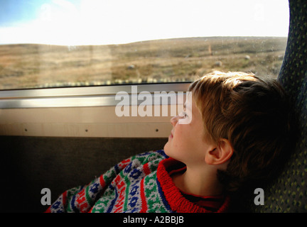 Ragazzo che guarda fuori in uno scenario paesaggistico mentre si viaggia su un treno Foto Stock