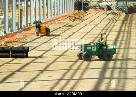 Costruzione nuovo grande magazzino edificio sviluppo sito dumper macchina funzionante al di sotto di unclad quadro siderurgico gettando ombre England Regno Unito Foto Stock