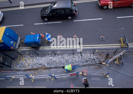 Cavi di posa lavori stradali telcomunicazioni BT cavi nel centro di Londra affollato cavi di posa lavori stradali telcomunicazioni BT con code traffico Foto Stock