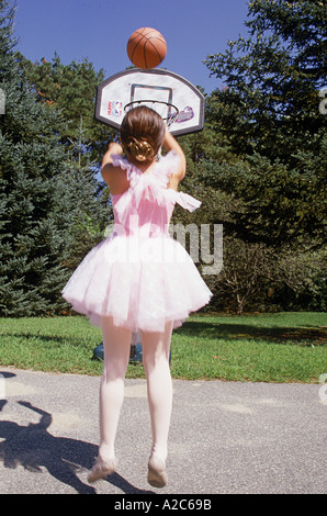 Ragazza in abito da ballerina tiri a canestro sul campo di pallacanestro Foto Stock