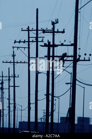 Immagine industriale di un elettricista sulla sommità di un palo di potenza su un molto nuvoloso giorno Foto Stock