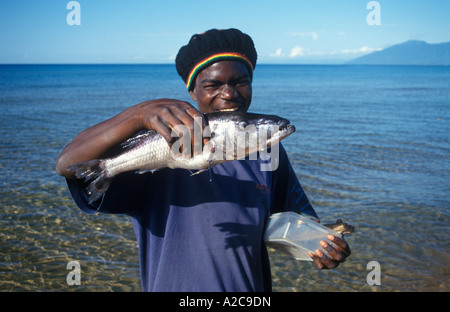 Nativo di una giovane uomo è la presentazione di un grande pesce che ha appena pescato nel Lago Malawi Foto Stock