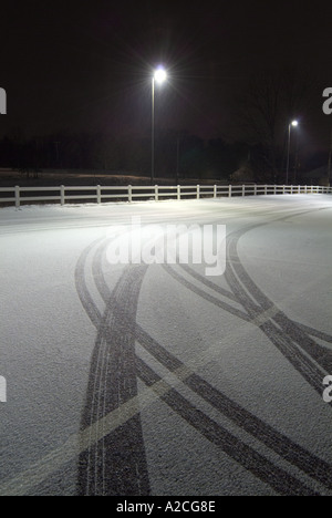 Tracce di pneumatici nella neve, parcheggio con luce Foto Stock