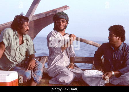 Oman. Al largo della costa di Muscat. Omani dhow capitano e due compagni mantenendo fargli compagnia mentre la voce per il porto Foto Stock