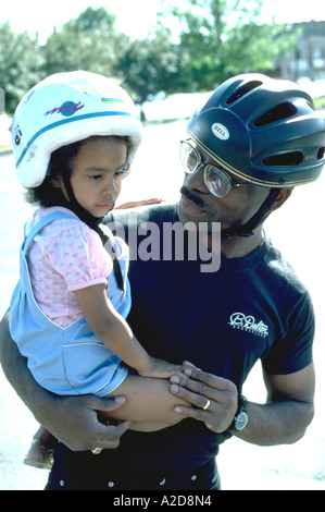 Padre figlia di contenimento che indossa caschi da bicicletta età 26 e 3. Minneapolis Minnesota USA Foto Stock