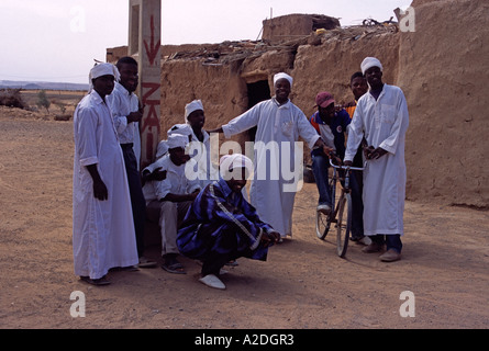 Gruppo di gnaoua musicisti in bianco e kaftans turbanti prendendo una pausa, Erg Chebbi, Sahara, Marocco Foto Stock