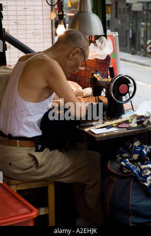 Dh Pottinger Street CENTRAL HONG KONG vecchio uomo cinese rammendo vestiti con cucitura a macchina Foto Stock