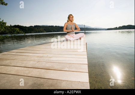 Donna che esercitano lo yoga sul pontile Foto Stock