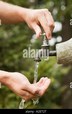 Mani coppettazione acqua dalla fontana, close-up Foto Stock