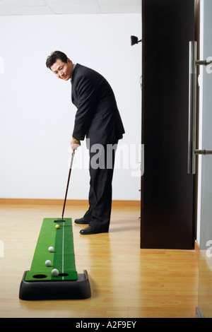 Il profilo laterale di un imprenditore la pratica del golf in una stanza Foto Stock