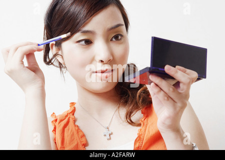 Close-up di una giovane donna tenendo un make-up e pennello una mano specchio Foto Stock