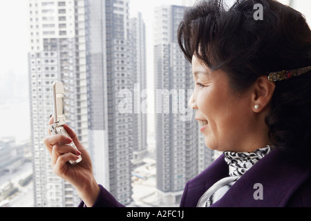 Profilo laterale di una imprenditrice guardando un telefono cellulare sorridente Foto Stock