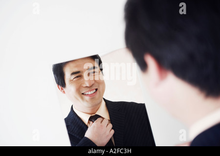 Vista posteriore di un imprenditore cercando in uno specchio la sua regolazione tirante Foto Stock