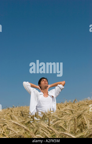 Giovane uomo in piedi in cornfield, mano a portata di mano Foto Stock