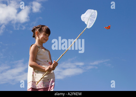 La ragazza (7-9) rete di contenimento cercando di catturare butterfly Foto Stock