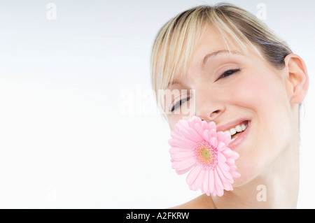 Giovane donna azienda fiore in bocca Foto Stock