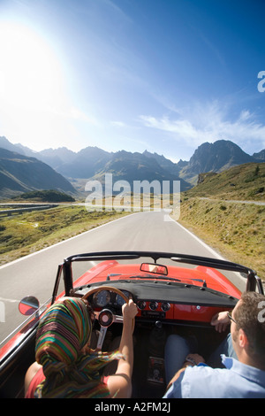 Austria, Alpi, giovane guida in auto convertibili, vista posteriore Foto Stock