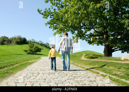 Padre e figlio camminando mano nella mano, vista posteriore Foto Stock