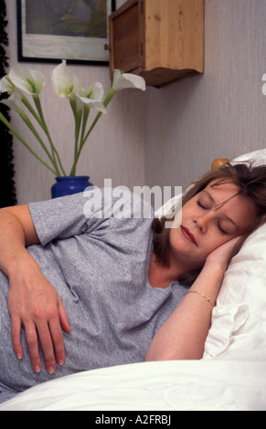 Fortemente incinta donna disteso addormentato al resto sul letto Foto Stock