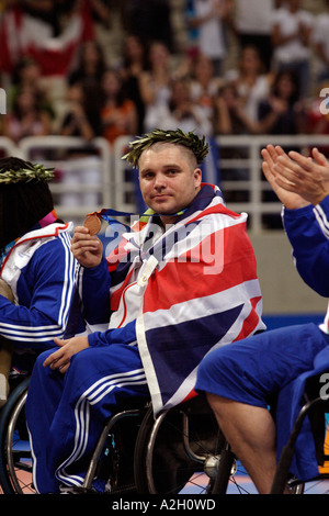 Drappeggiati alla Union Jack Jon Pollock di GBR mostra la sua medaglia di bronzo per la mens aprire la pallacanestro Atene 2004 Giochi Paralimpici Foto Stock