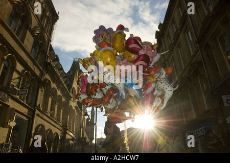 Uomo di vendere un gran mucchio di palloncini in un centro città street retroilluminati da Sun Foto Stock