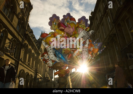 Uomo di vendere un gran mucchio di palloncini in un centro città street retroilluminati da Sun Foto Stock