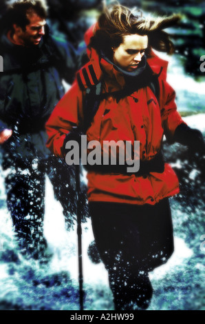 Donna età 20-25 indossando vestiti di alpinismo a piedi attraverso un fiume. Foto Stock