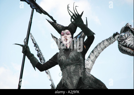 Signora in abito dragonlike esecuzione di teatro di strada atto visto da sotto contro il cielo blu Foto Stock