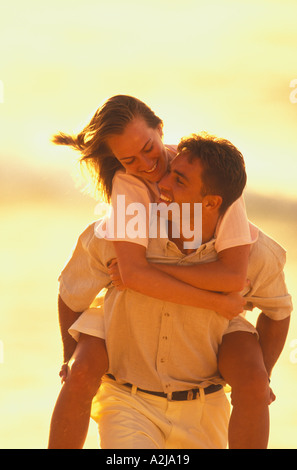 Gru per l uomo la sua testa indietro a guardare la donna sorridente ha felicemente porta sovrapponibile all'aperto in una calda luce dorata Foto Stock